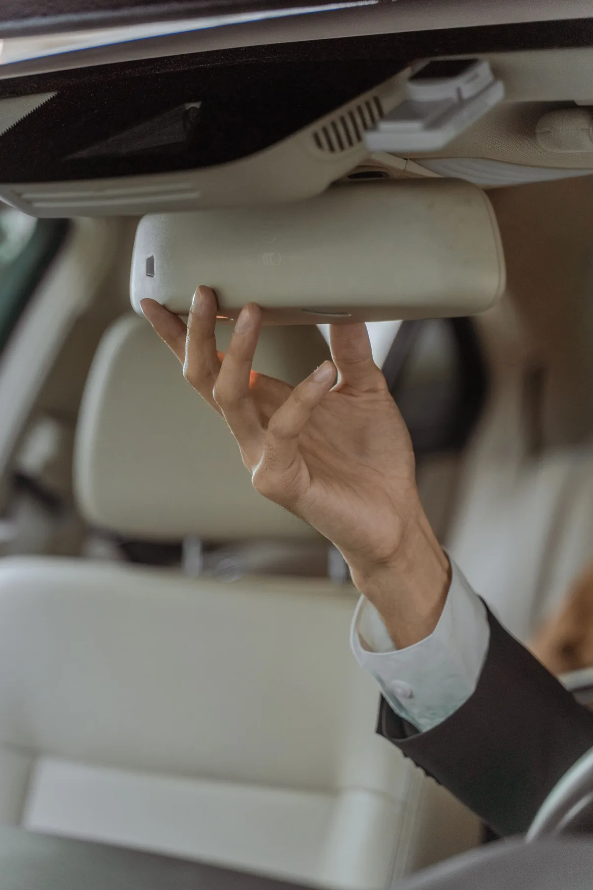 Representative close-up of a chauffeur adjusting a rear-view mirror